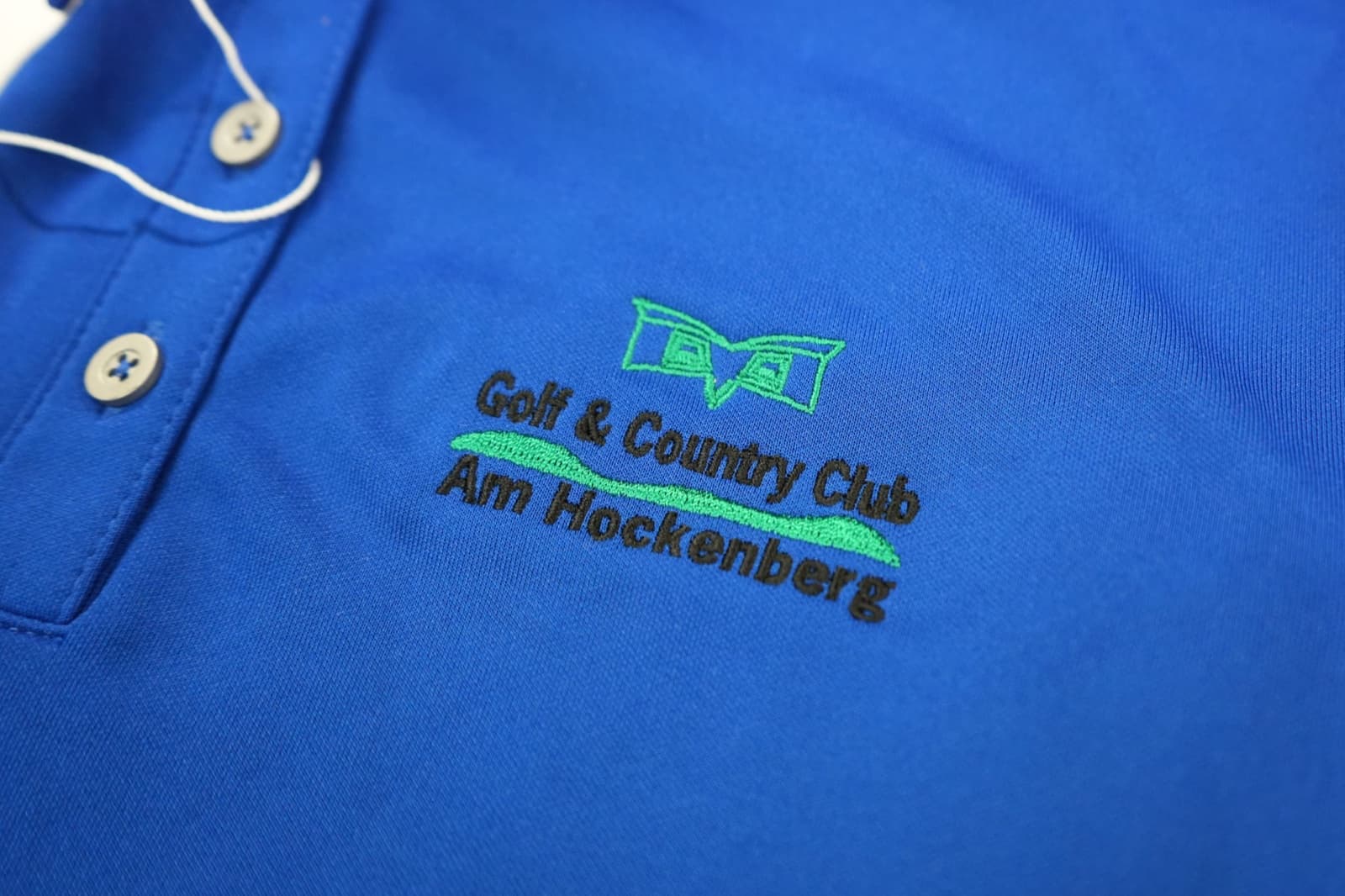 Embroidered corporate logo on the left chest of a navy polo shirt